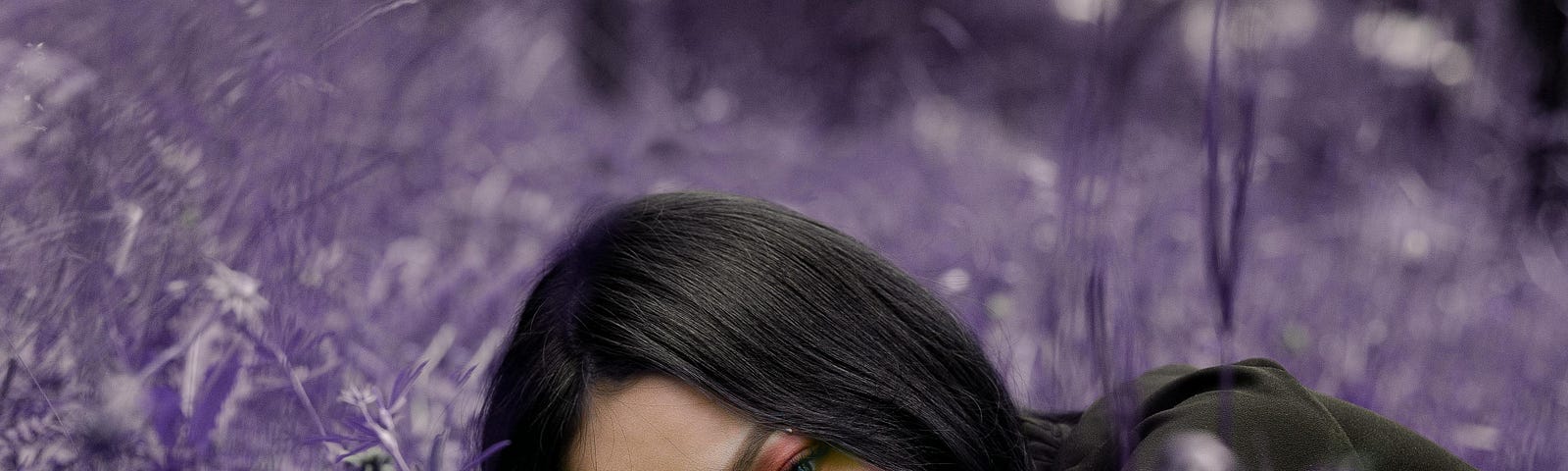 A woman with make-up lying among purple flowers.