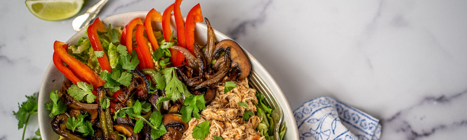 A large bowl filled with salad, chicken, fajita vegetables, and avocado.