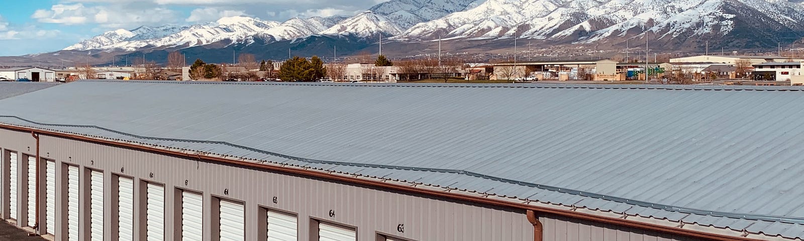 Bird’s eye view shot of storage unit with mountains and clouds off in the background.