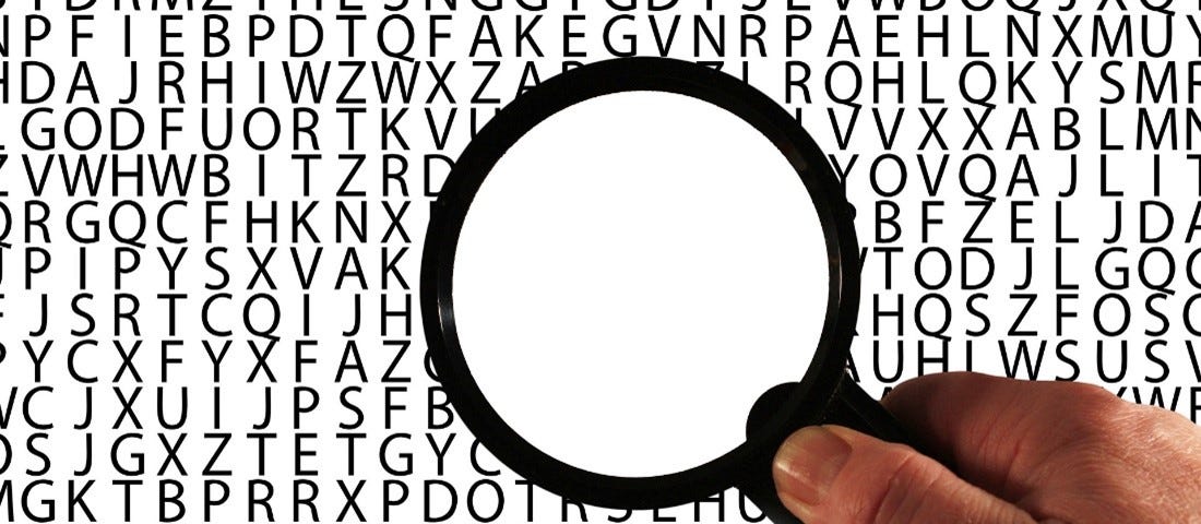 Magnifying glass over lines of randomized capital letters