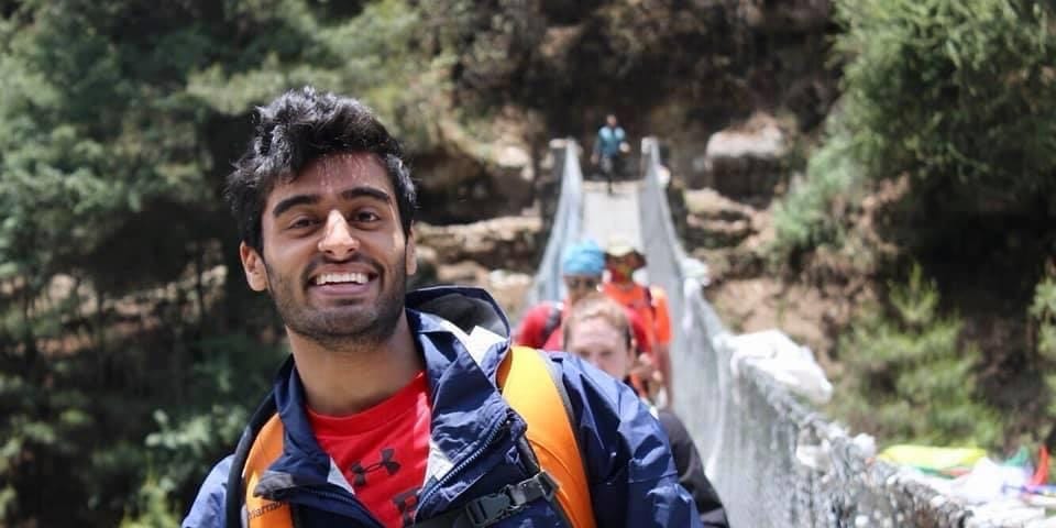 Zubin Patel hiking across a rope bridge with other hikers.