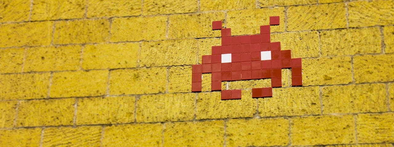 Red tiles form an alien head on a yellow brick wall.