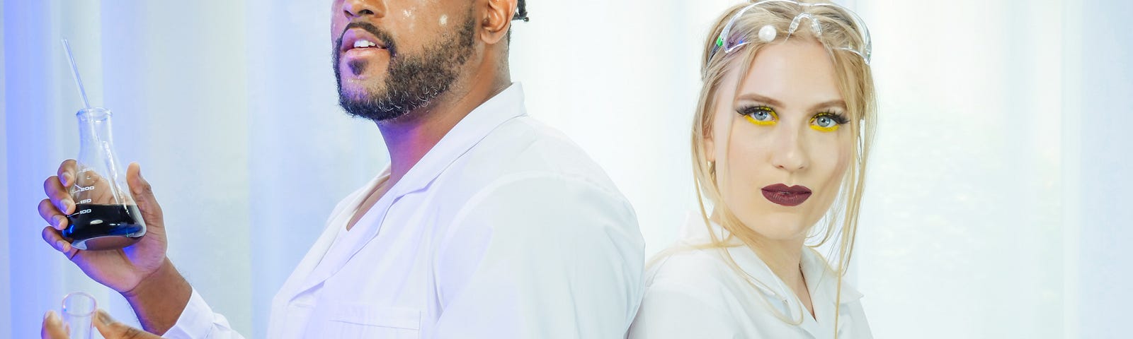 A man and a women dressed in scientists’ coat hold chemicals in their hands