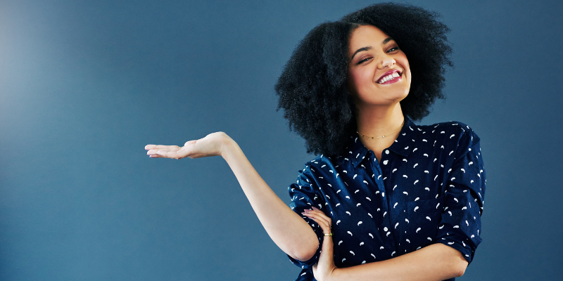 African-American woman smiling and holding up her hand — Writers With These Three Qualities Make 23% More Per Year