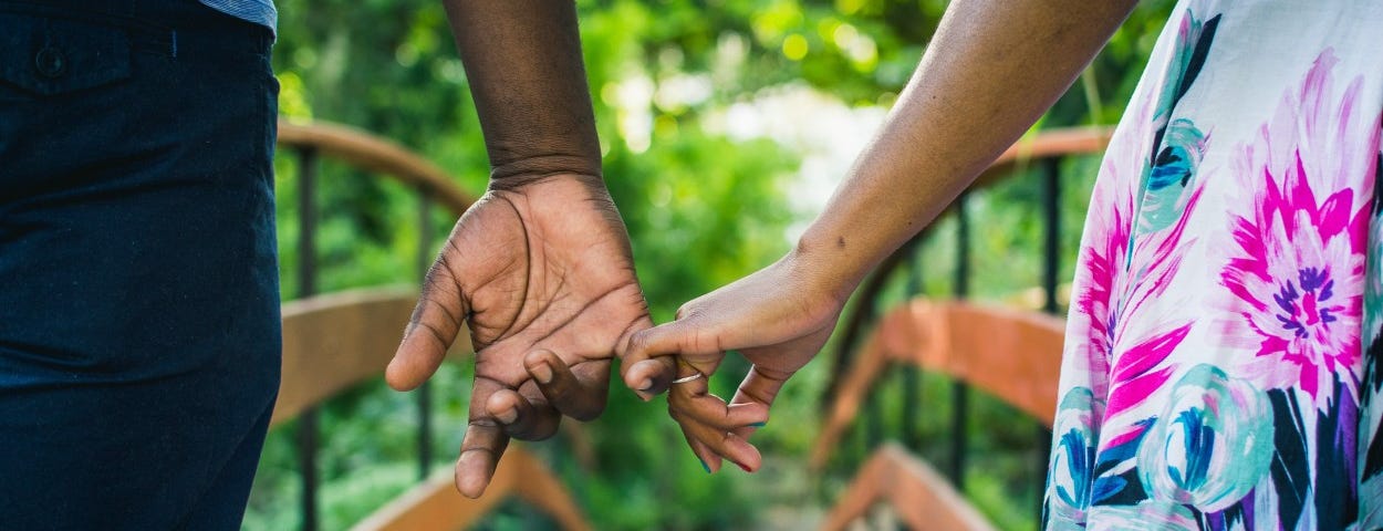 A couple holds hands on a bridge.