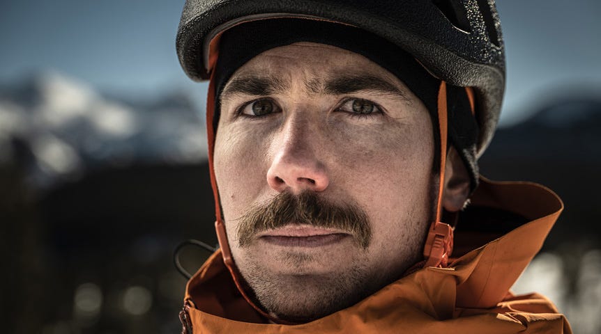 Close-up of snow sportsman in helmet and orange jacket