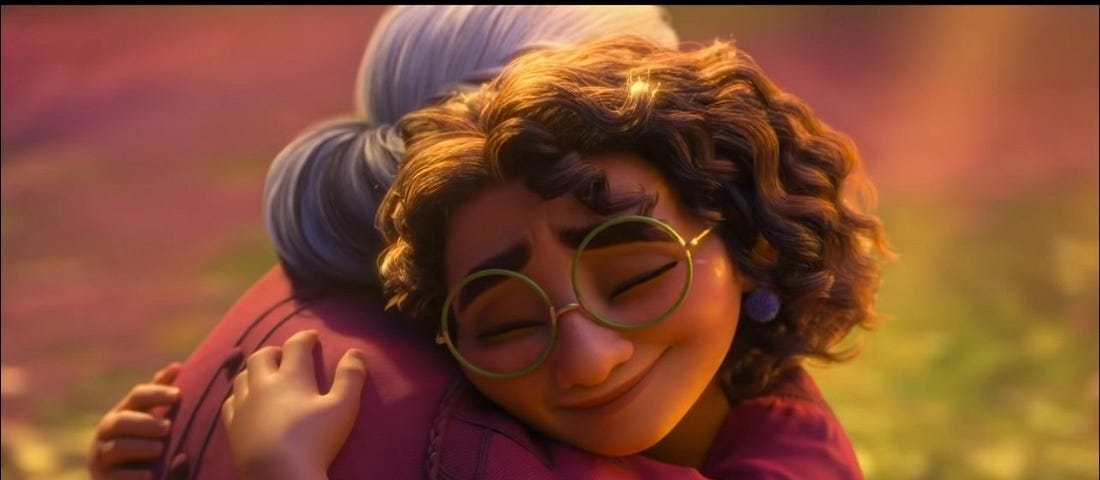 A still from Encanto. Mirabel and Alma/Abuela hug.