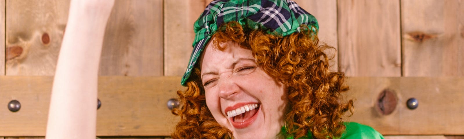red haired young woman dressed for St. Patrick’s day and carrying a green flagon