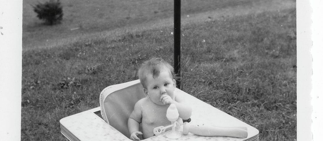 The author as a baby in a square feeding seat/table