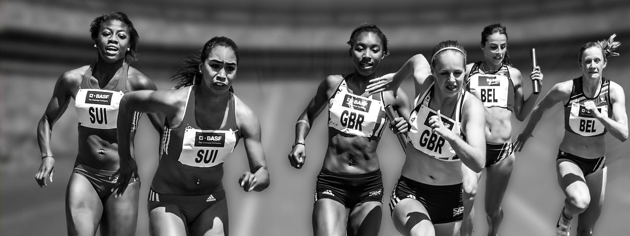 Black and white picture of six female runners racing and wearing sport bibs.