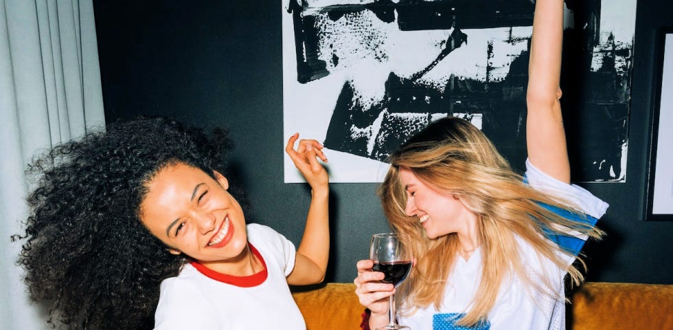 Two young women eating pizza, drinking wine, and having fun.