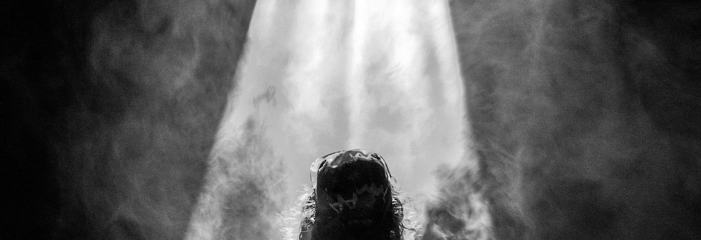 Black and white pic of someone standing in a beam of light