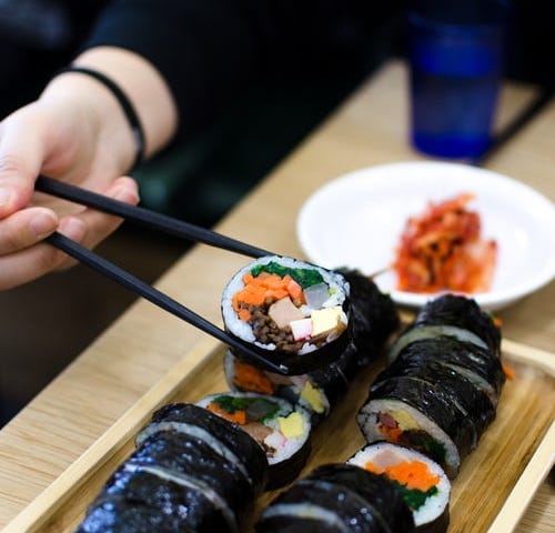 Person eating kimbap with chopsticks