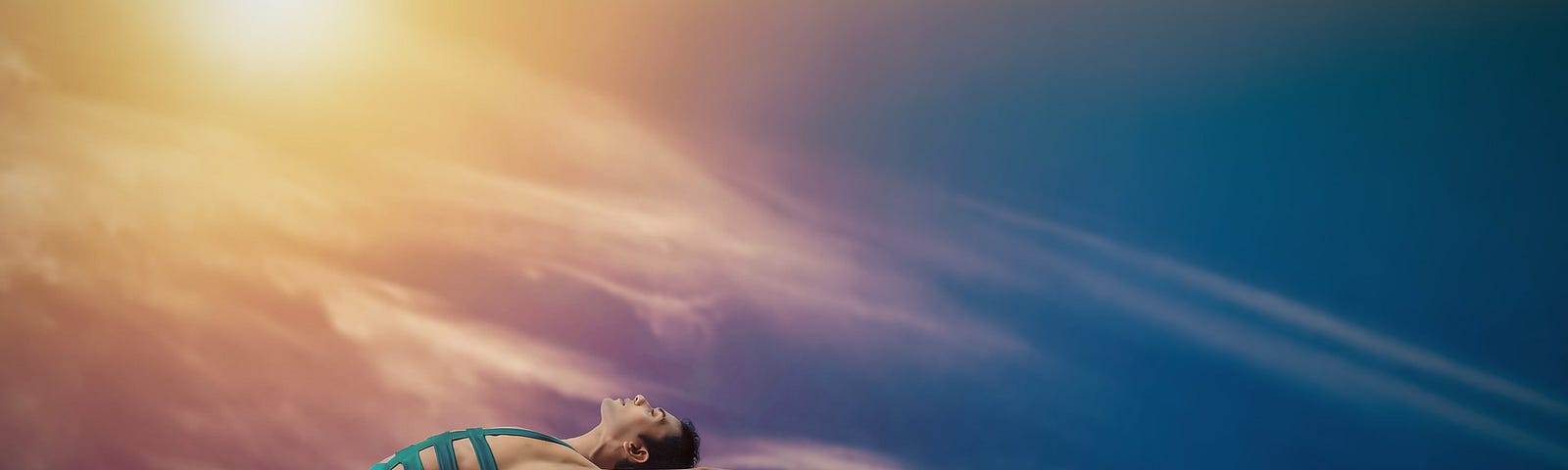 Man doing yoga pose on a rock wall with the sunset in the background.