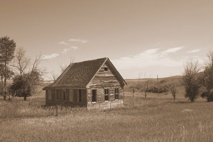 Sepia photo of an abandoned farmhouse in the prairie