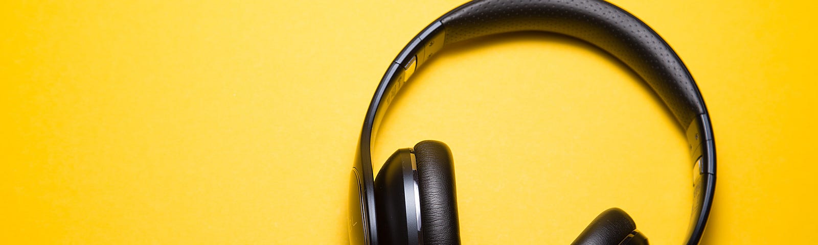 black headphones on a yellow background for listening to a data science podcast