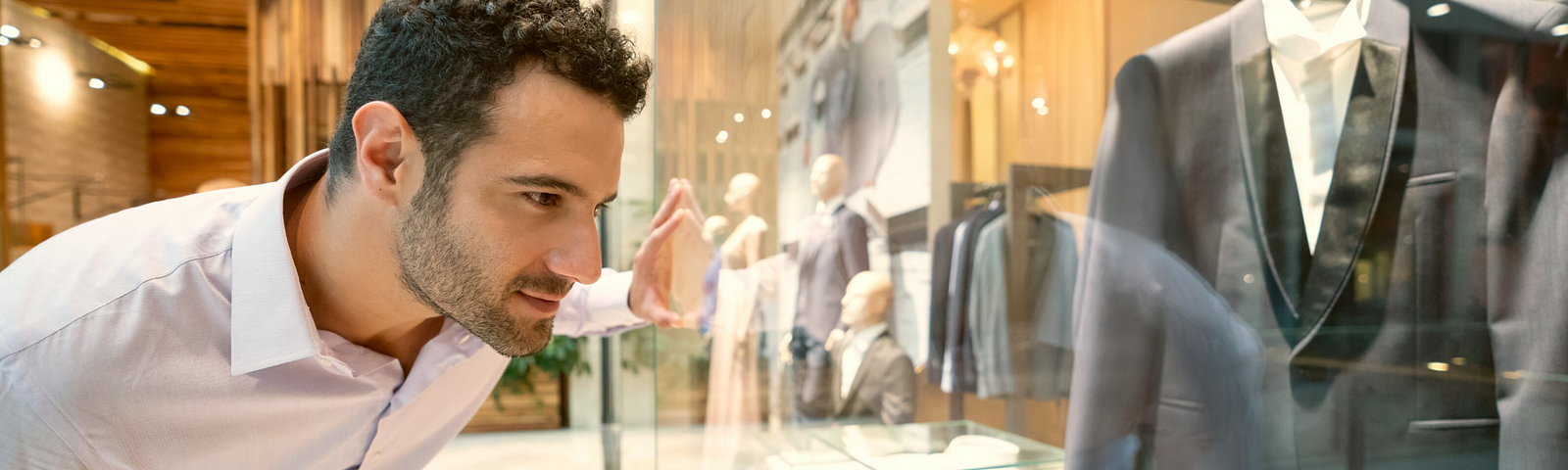 Man shopping, leaning over, looking through store window at display