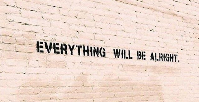 Parede de tijolos aparentes com a frase em inglês “Everything will be alright”, ou “Tudo ficará bem”, em português.