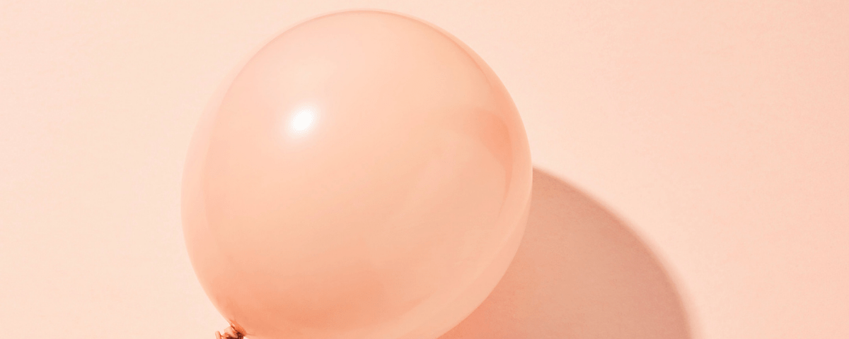 A pink balloon on a pink surface.