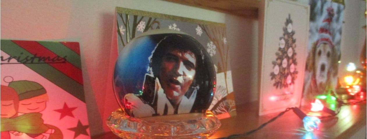 An Elvis Presley Christmas ornament is displayed next to Christmas cards