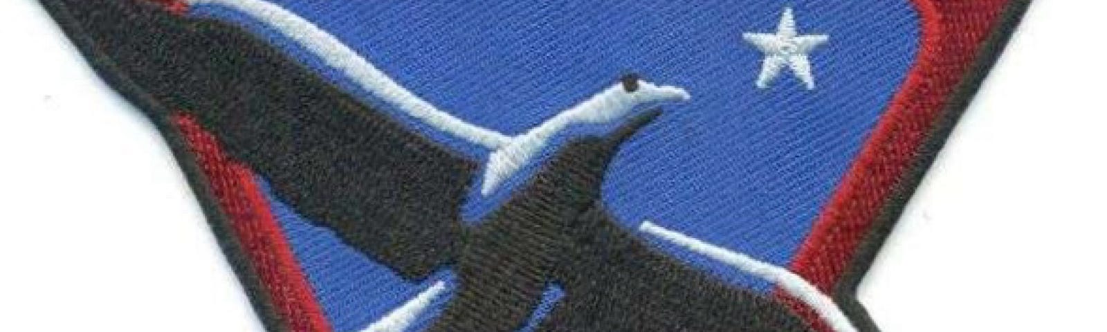 An NX Project Patch with a dark blue bird.