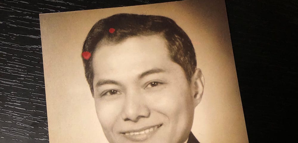 Sephia-colored square print photo of a young Filipino man dressed in a suit and tie smiling at the camera.