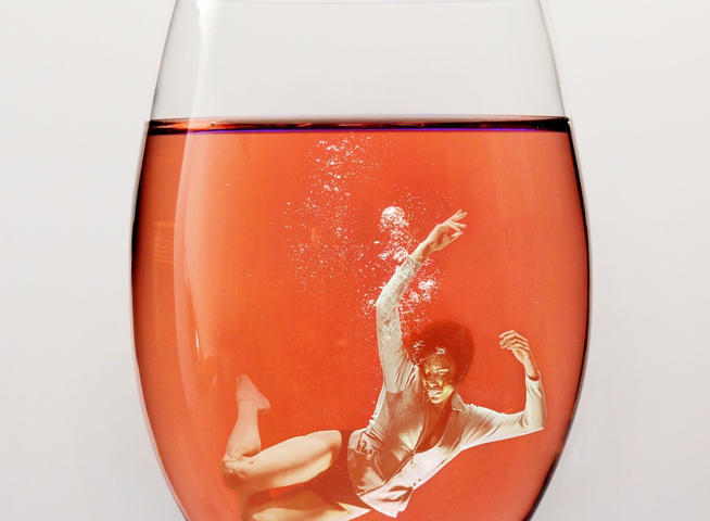 Woman drowning in a glass of wine to show the overwhelming nature of alcohol addiction