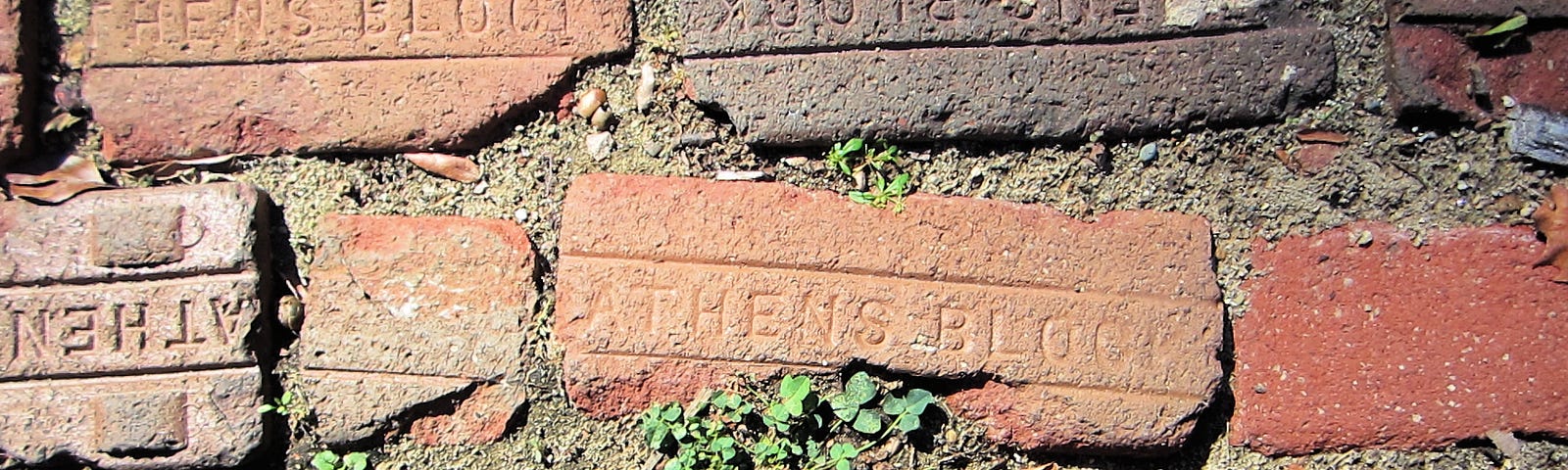 Photograph of brick pathway laid with red bricks. The bricks are stamped with ATHENS BLOCK.