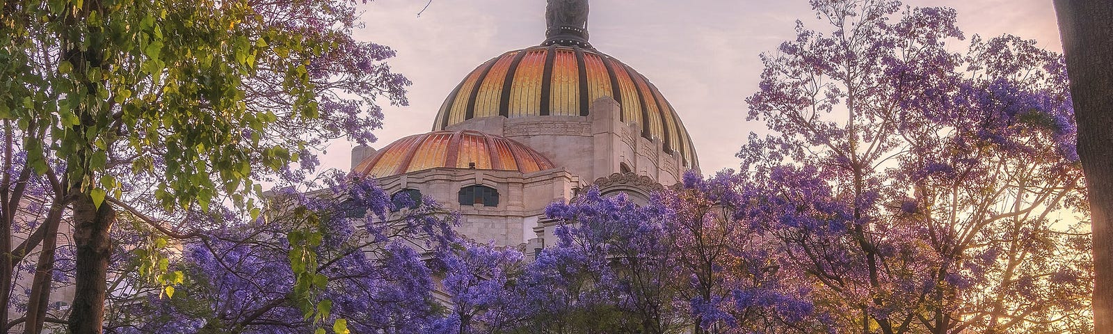 A golden domed palace peeks over the top of flowering purple trees.