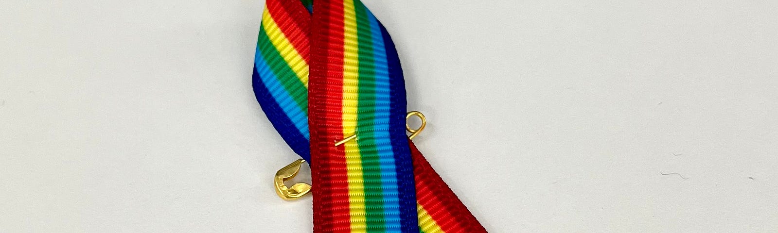 A rainbow ribbon secured with a safety pin.