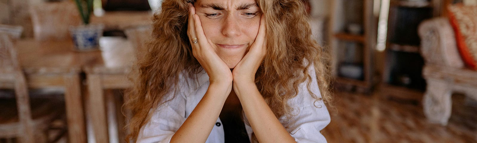 A woman sitting at a desk in front of a computer, looking slightly overwhelmed as she begins a task. Her expression shows determination mixed with struggle, capturing the challenge of starting. The image represents the concept of finding flow in everyday tasks, highlighting simple hacks to kickstart productivity, focus and overcome initial resistance.