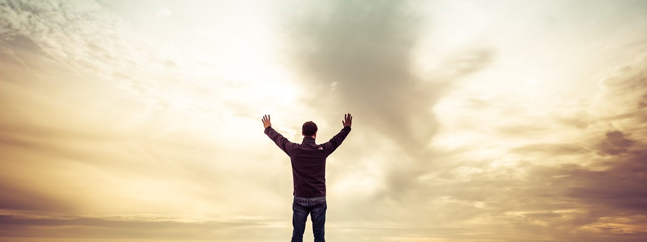 Man standing with upraised hands in worship