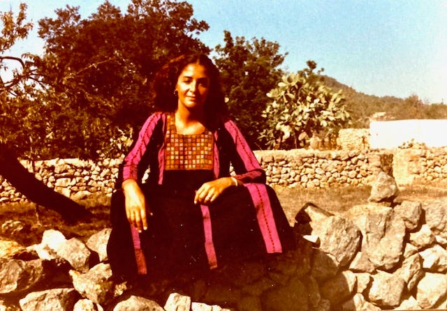 A young woman sitting on top of a rock wall wearing a tribal dress in Spain