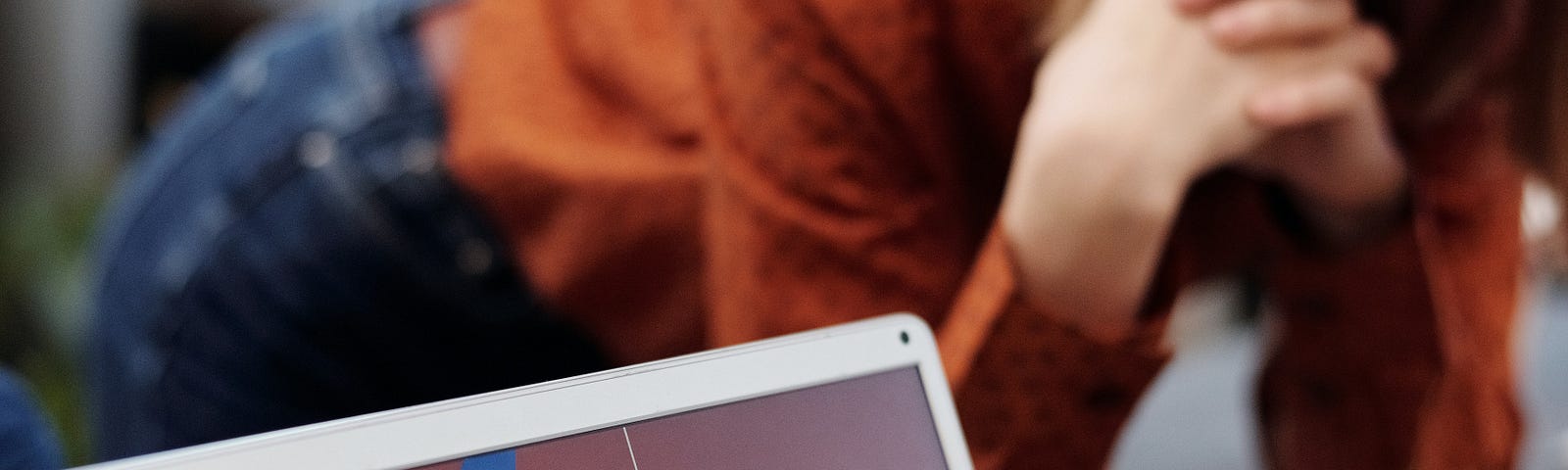 Lady in jeans and orange top leaning over table to see what could be Medium stats screen that says “Moving Forward”.