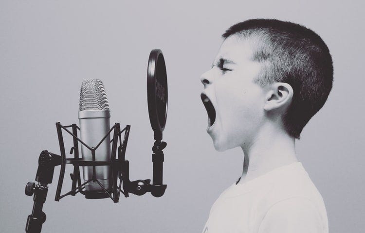 Image of a boy in front of a recording mic, shouting out loud