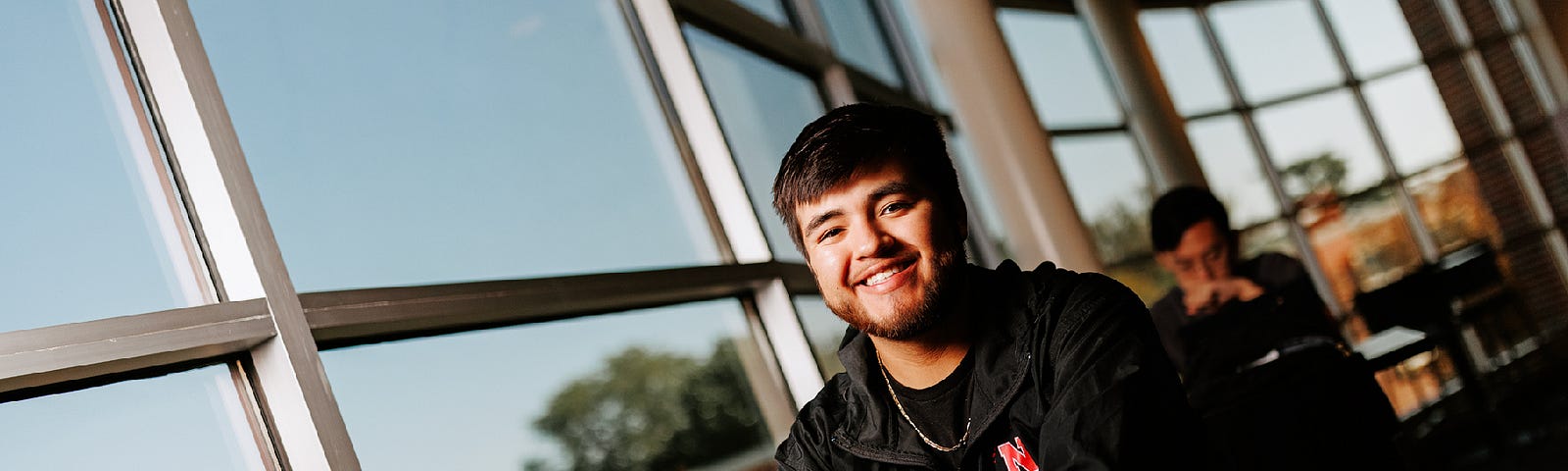 Isaac poses for a photo by the windows of the Gaughan Center