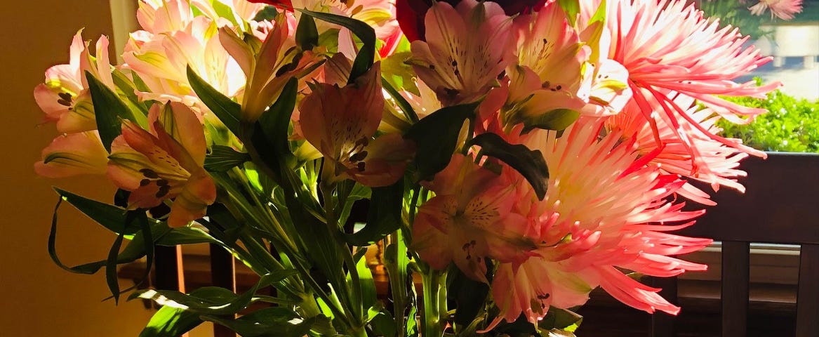 a beautiful bouquet on the table in pink, yellow and white in a pink vase.