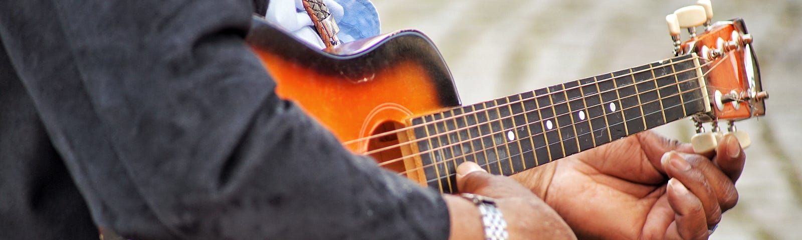 #pracegover: Homem negro de roupa preta afinando violão.