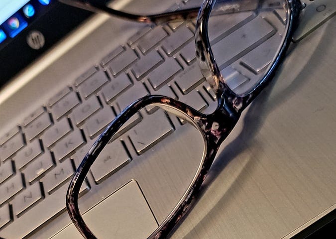 Reading glasses resting on a laptop keyboard.