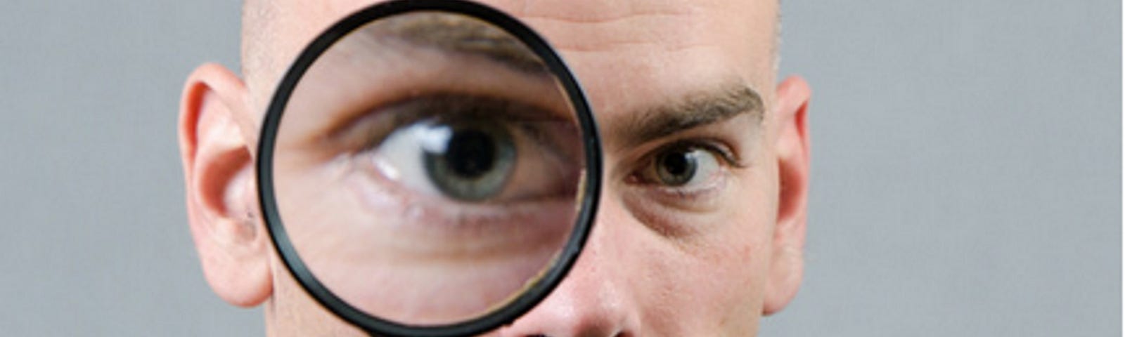 White male looking through magnifying glass