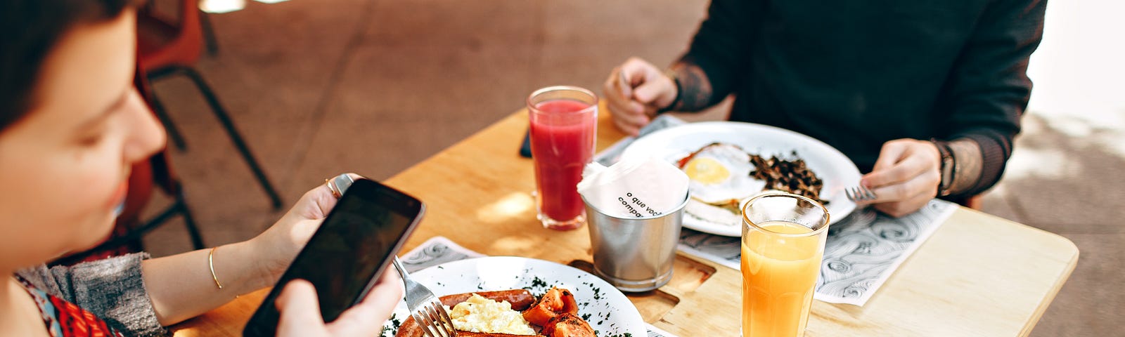 Young couple taking photo of meal as they sit at a bar-top restaurant table.