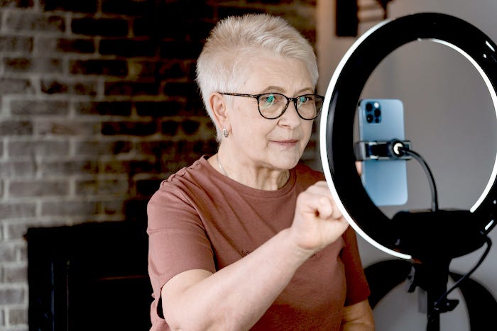 Middle aged woman looking into smartphone mounted on a light.