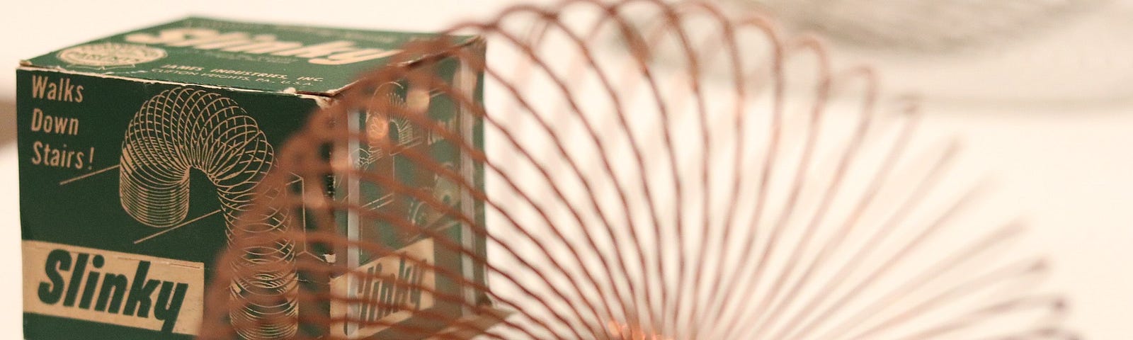 The vintage Slinky box with a partially blurred Slinky fanned out in the foreground.