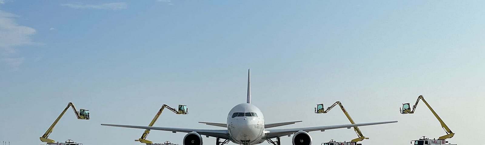 A FedEx aircraft on the de-icing pade, surrounded by de-icing vehicles.