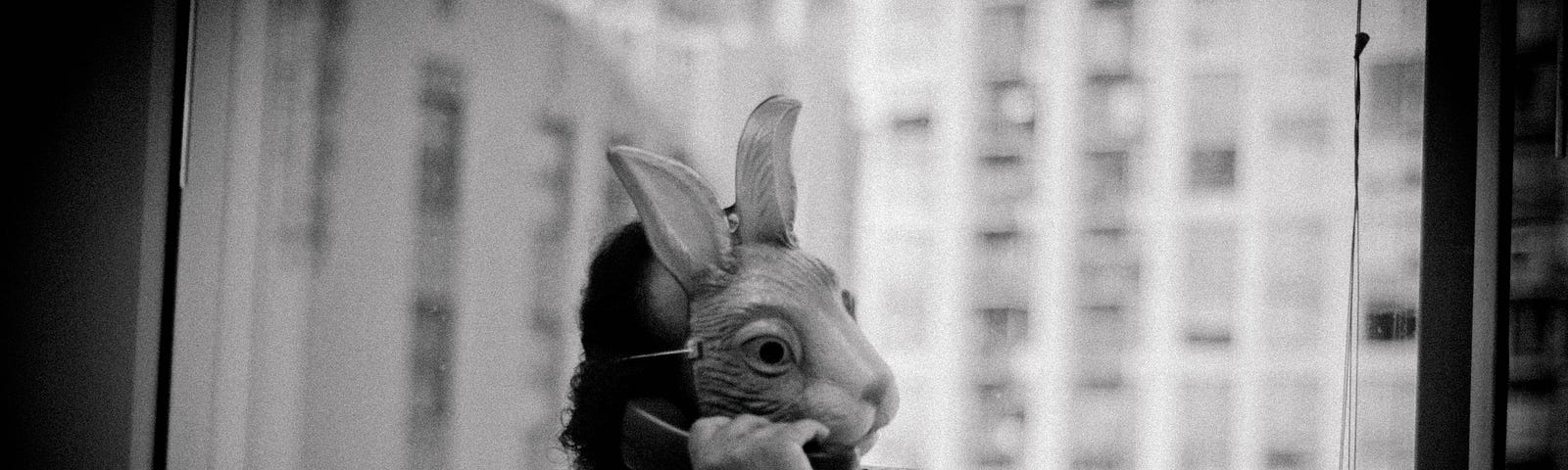 A man wearing a rabbit mask on the phone.