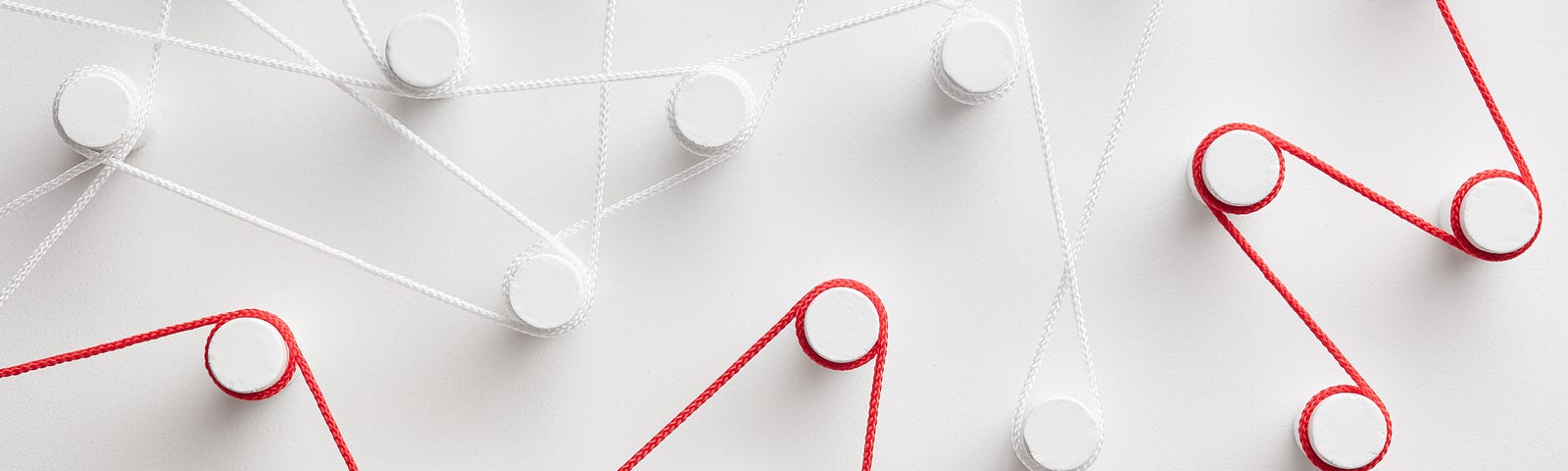 Close-up image of contrasting red and white strings strung between pegs over a white background.