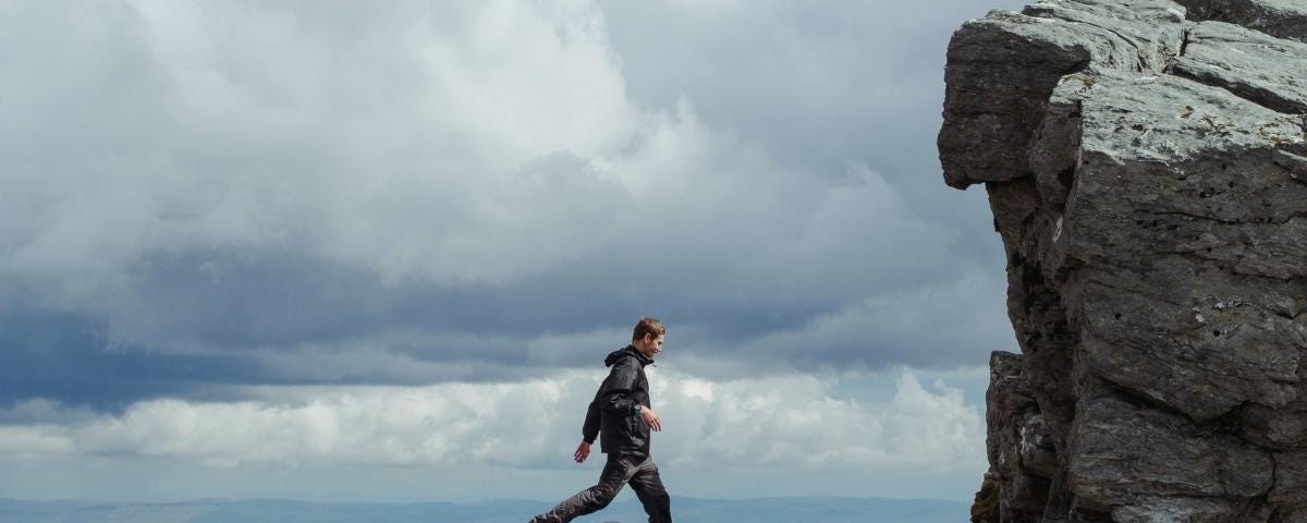 Man walking ontop of large rocks high up