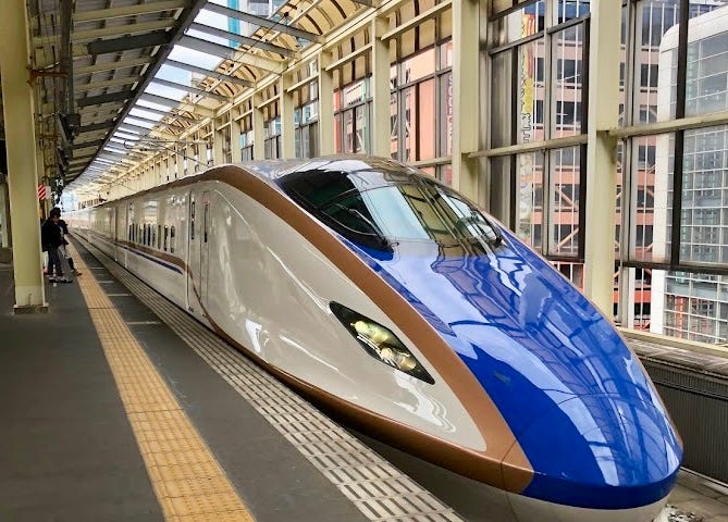 Shiny blue and white bullet train in station.