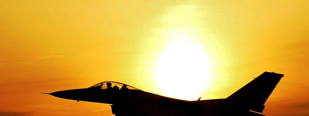 Airplane jet fighter silhouette flying in orange and yellow sunrise