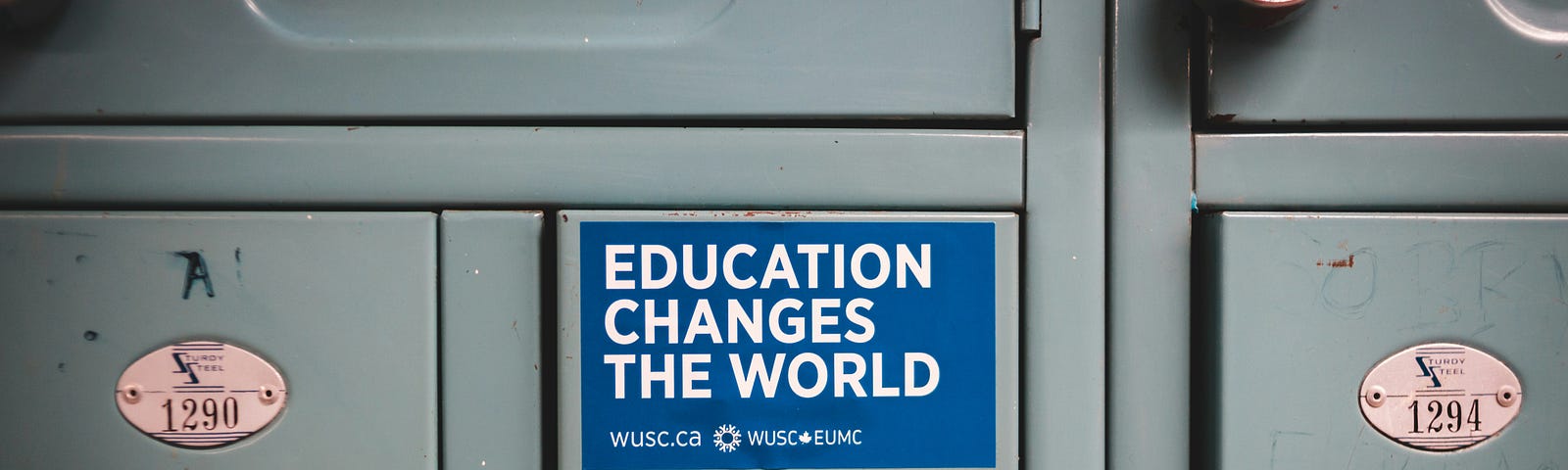 Grey metal lockers, one with a blue “Education Changes the World” sticker in white block capitals.